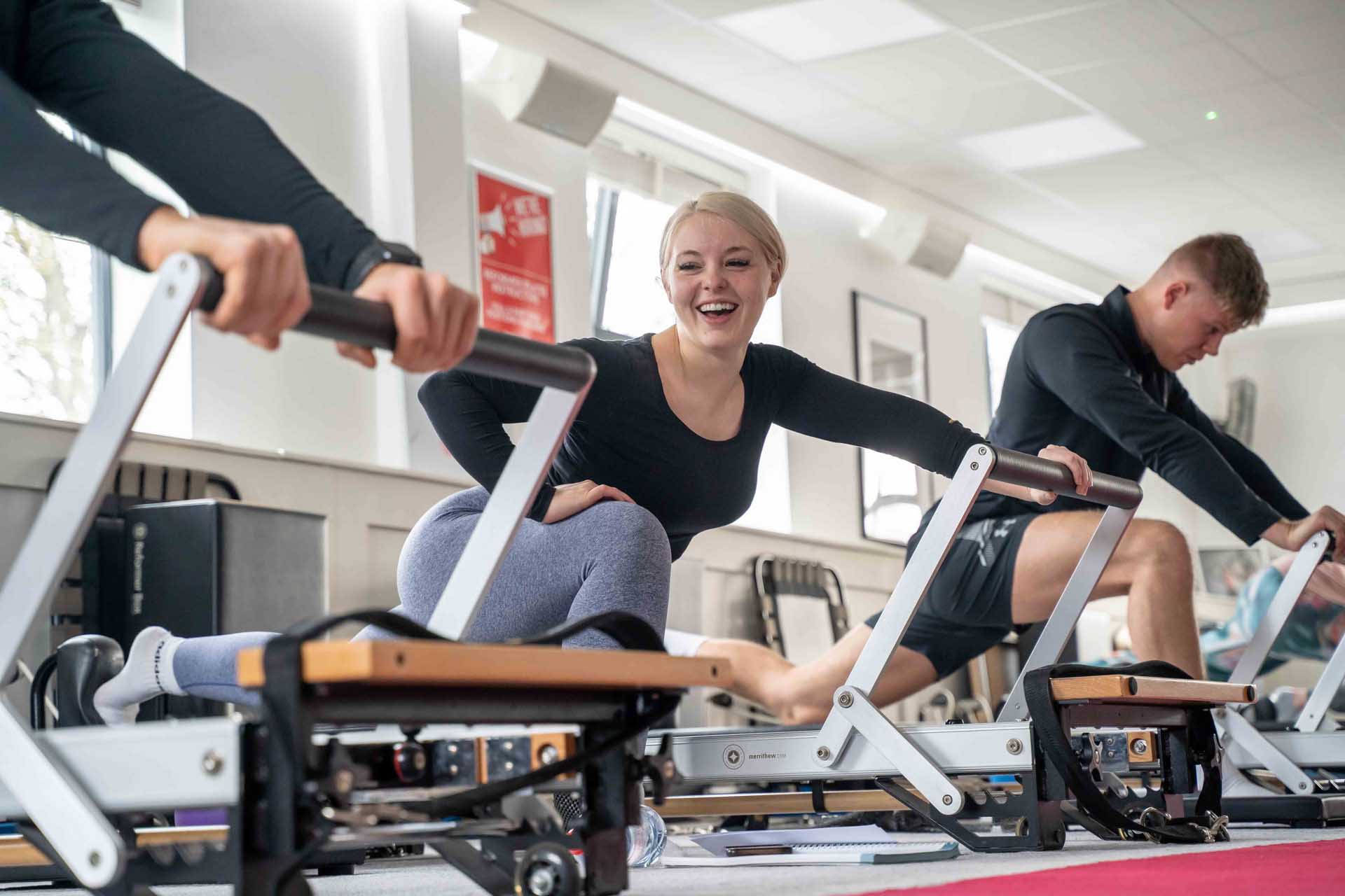 A 50-year-old trainer teaches a young girl to practice Pilates on an