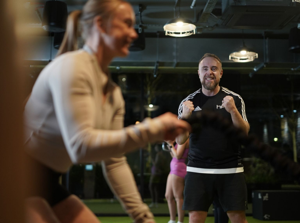 Personal trainer with client using battle ropes