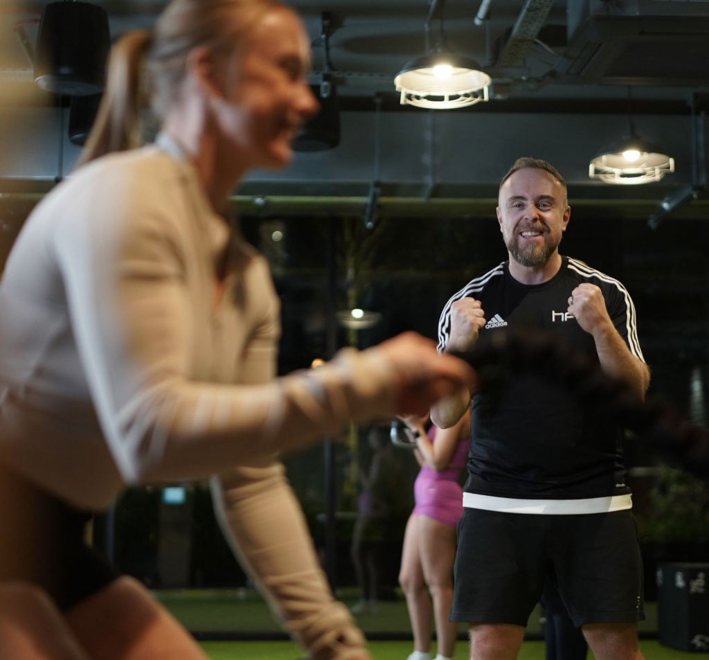 Personal trainer with client using battle ropes